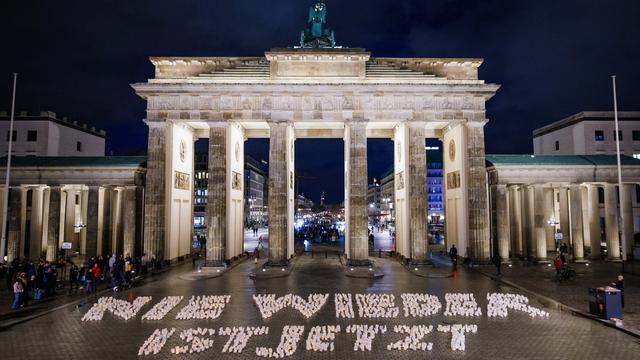 Des bougies forment le slogan "Plus jamais ça", lors d'une manifestation devant la porte de Brandebourg à Berlin, en Allemagne, le 26 janvier 2024, un jour avant la Journée internationale de commémoration de l'Holocauste. [Keystone - EPA/CLEMENS BILAN]