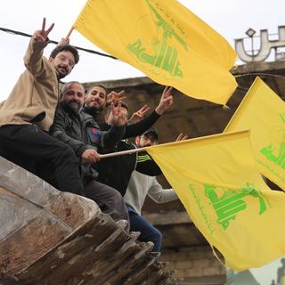 Des hommes libanais qui fêtent la paix avec des drapeaux du Hezbollah, après le cessez-le-feu avec Israël du 27 novembre. [Keystone/AP Photo - Mohammed Zaatari]