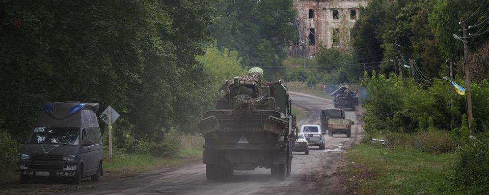 Des véhicules militaires circulent près de la frontière russo-ukrainienne dans la région de Sumy, en Ukraine, le 13 août 2024. [Keystone - AP Photo/Evgeniy Maloletka]