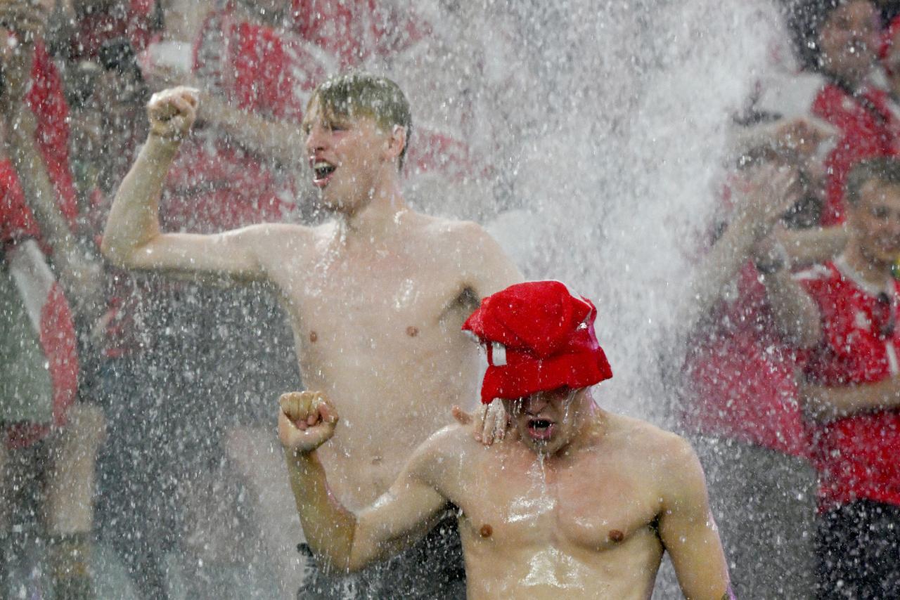 Des supporters danois "prennent une douche" durant le passage d'un orage au-dessus du Signal Iduna Park. Le match de l'Euro entre l'Allemagne et le Danemark a dû être interrompu en conséquence. [KEYSTONE - FEDERICO GAMBARINI]