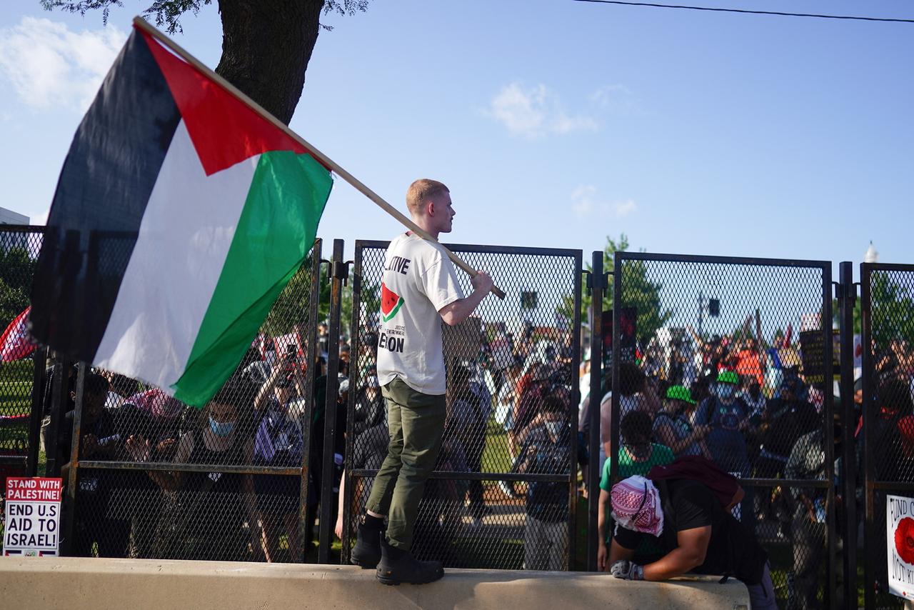 Un manifestant portant un drapeau palestinien se tient à l'intérieur du périmètre de la convention démocrate américaine à Chicago, après avoir forcé une barrière. [KEYSTONE - WILL OLIVER]