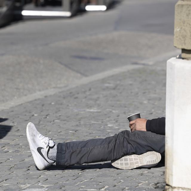 Un homme mendie sur la place du Bourg-de-Fourg, à Genève. [Keystone - Salvatore Di Nolfi]