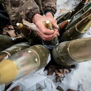 Un soldat ukrainien range des obus de 155 mm  dans la région de Zaporizhia, au sud-est de l'Ukraine, le 14 janvier 2024. [KEYSTONE - KATERYNA KLOCHKO]