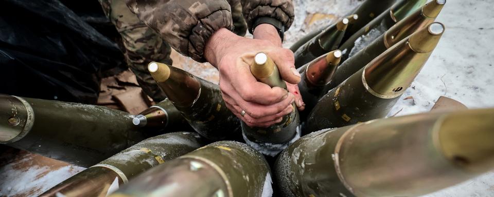 Un soldat ukrainien range des obus de 155 mm  dans la région de Zaporizhia, au sud-est de l'Ukraine, le 14 janvier 2024. [KEYSTONE - KATERYNA KLOCHKO]