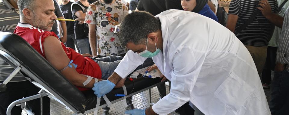 Un homme donne son sang au Liban pour soigner les personnes blessées par les explosions des derniers jours. [KEYSTONE - EPA/WAEL HAMZEH]