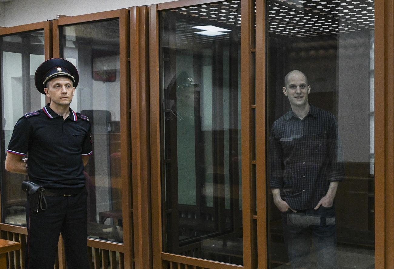 Le journaliste Evan Gershkovich se tient dans une cage de verre avant une audience au tribunal régional russe de Sverdlovsk, à Ekaterinbourg, le 26 juin 2024. [KEYSTONE - STRINGER]