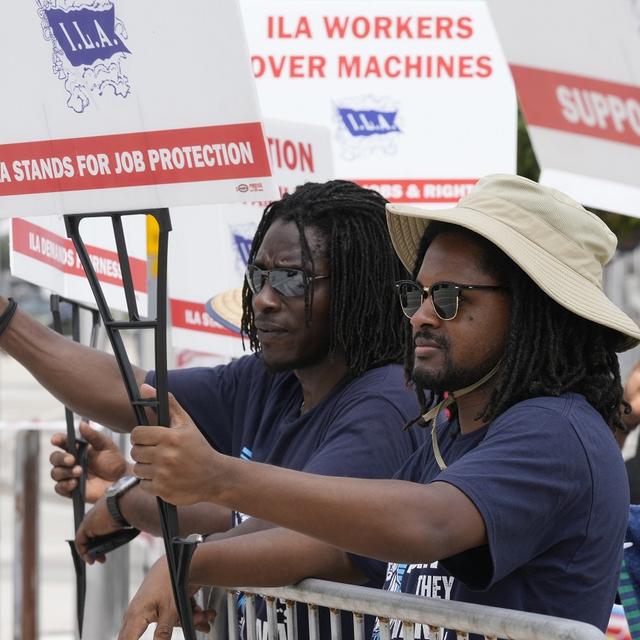 Dockworkers from Port Miami display signs at a picket line, Thursday, Oct. 3, 2024, in Miami. [AP Photo/Keystone - Marta Lavandier]