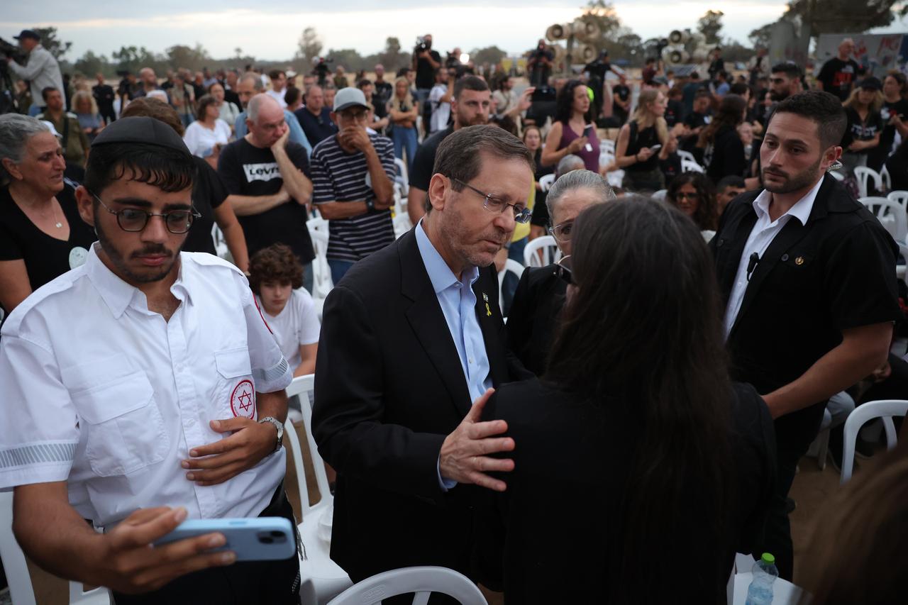 epa11646663 Israeli President Isaac Herzog embraces a family member of victims killed at the Supernova music festival while attending a gathering in memory of their relatives, at the Supernova memorial site for the victims of the 07 October 2023 Supernova music festival attack, near Kibbutz Re'im, close to the border with the Gaza Strip, in southern Israel, 07 October 2024. According to Israeli police, more than 360 Israelis were killed at the SuperNova music festival on 07 October 2023 by Hamas militants that stormed the area during a surprise attack launched from the Gaza Strip. October 07, 2024 marks one year since the Palestinian militant group Hamas launched a surprise attack on Israel, killing 1,400, and one year since Israel began its war on Gaza, killing more than 41,000 and destroying the Palestinian enclave. EPA/ABIR SULTAN [Keystone - Abir Sultan]