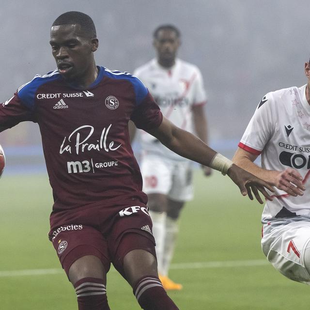 Le milieu genevois Dereck Kutesa, gauche, lutte pour le ballon avec le milieu valaisan Luca Zuffi, droite, lors de la rencontre de football de Super League entre le Servette FC et le FC Sion le samedi 13 mai 2023 au stade de Geneve. [Keystone - Martial Trezzini]