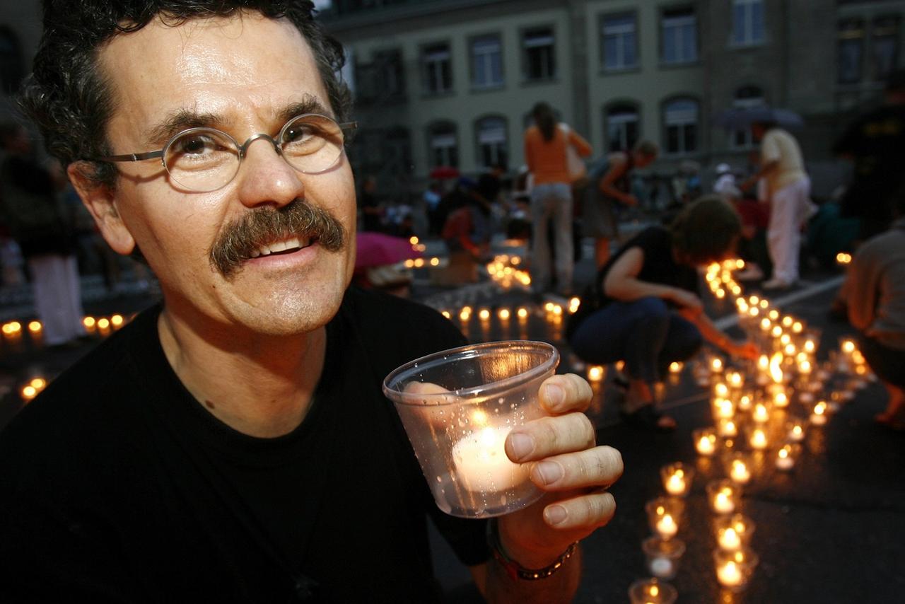 L'artiste Muma allume l'une des dizaines de milliers de bougies disposées à Lausanne le 31 juillet 2006. [KEYSTONE - LAURENT GILLIERON]