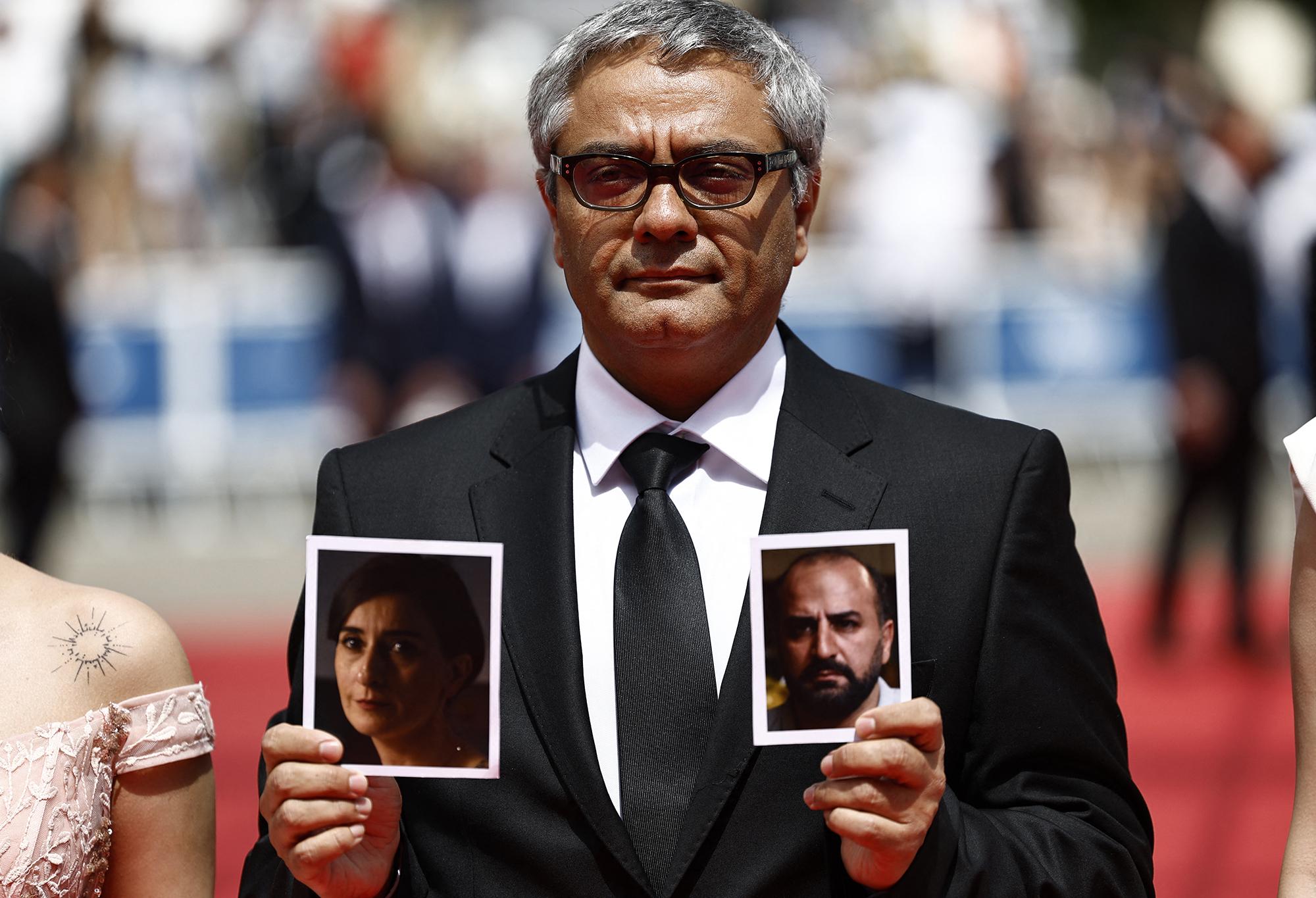 Le réalisateur iranien Mohammad Rasoulof brandissant les photos des acteurs de son film Missagh Zareh et Soheila Golestani sur le tapis rouge du 77e Festival de Cannes. [AFP - SAMEER AL-DOUMY]