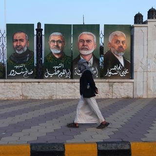 A passerby looks at paintings depicting (R-L) Hamas leader Yahya Sinwar, late Hamas leader Ismail Haniyeh and late Hezbollah military commanders Ibrahim Aqil, Saleh Sorour and Fuad Shukr, on display as part of an outdoor art exhibition in solidarity with the Lebanese and Palestinian people amid high tensions in the Middle East, in Sana'a, Yemen, 12 October 2024. The exhibition titled 'Our support to the Palestinians and the Lebanese people' features over 50 paintings by Yemeni artists on display on the fence of the Al-Shaab Mosque in Sana'a in solidarity with the Lebanese and Palestinian people amid Israel's military operations in Lebanon and the Gaza Strip. The exhibition runs for an indefinite period. [EPA/Keystone - YAHYA ARHAB]