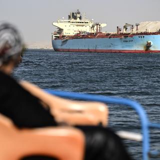 Une personne observe un navire rouillé qui traverse le Canal de Suez à Ismaïlia en Égypte.