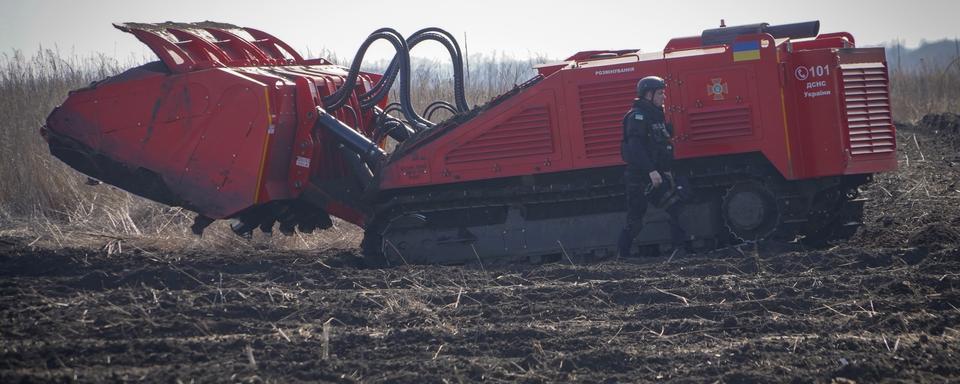 Une machine anti-mines nettoie un champ en Ukraine, dans la région de Kharkiv. [Keystone - Andrii Marienko]