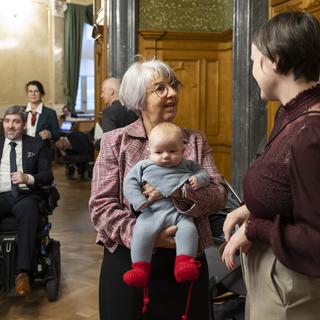 Elisabeth Baume-Schneider portant le bébé de la conseillère nationale socialiste bâloise, Sarah Wyss. 19 décembre 2024 à Berne, en Suisse. [KEYSTONE - Peter Klaunzer]