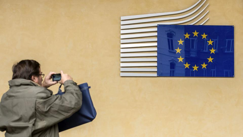 Un touriste devant l'enseigne du quartier général de la Commission européenne, à Bruxelles. [KEYSTONE - GEERT VANDEN WIJNGAERT]