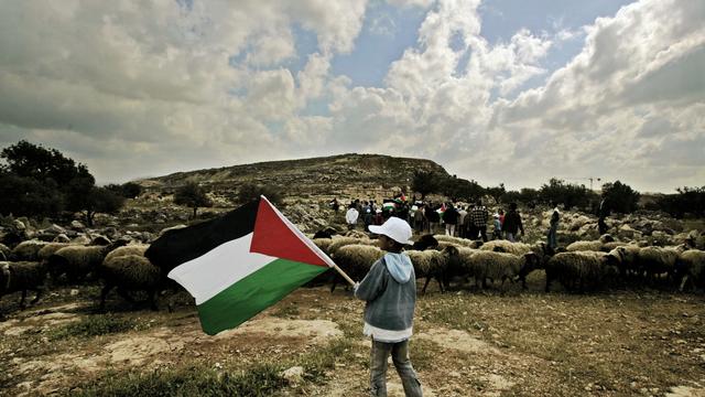 Un garçon palestinien tient un drapeau palestinien lors d'une manifestation pour marquer la Journée de la Terre. [KEYSTONE - MUHAMMED MUHEISEN]