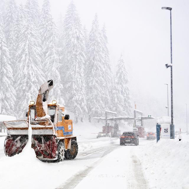 Un chasse-neige dégage la neige de la route devant le portail du chargement de voitures Vereina devant le portail à Klosters le dimanche. [Keystone - Til Buergy]