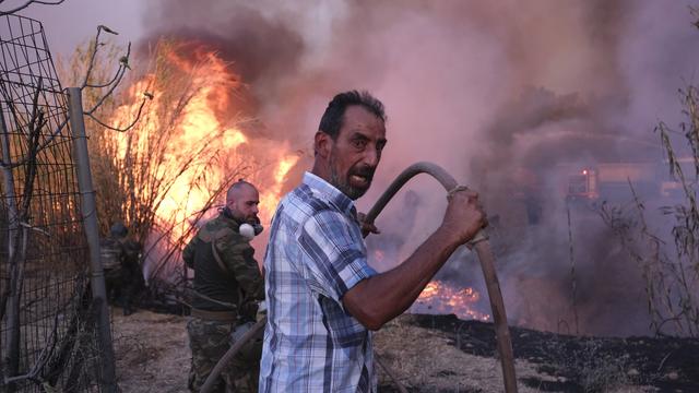 Des volontaires tentent d'éteindre l'incendie dans le nord d'Athènes. [KEYSTONE - AGGELOS BARAI]