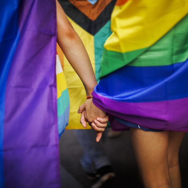 Deux personnes avec le drapeau LGBTQI+ à une Pride. [Keystone - Michael Buholzer]