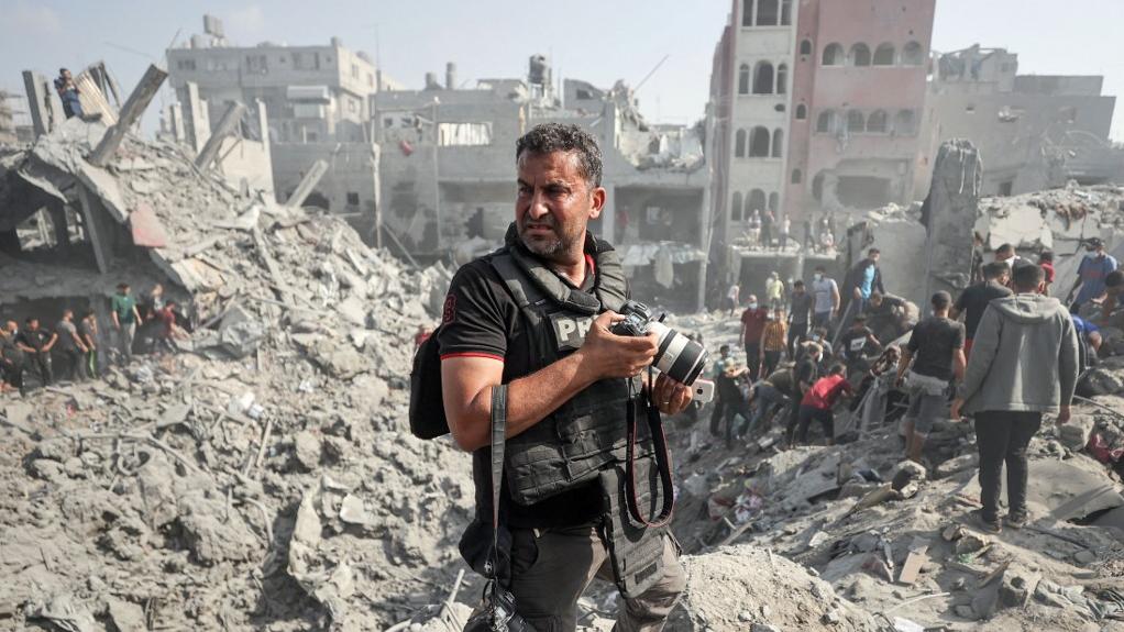 Le photographe palestinien Mahmud Hams, basé à Gaza, prend des photos des bâtiments détruits par les bombardements israéliens dans le camp de réfugiés de Bureij, dans le centre de la bande de Gaza, le 2 novembre 2023. [AFP]