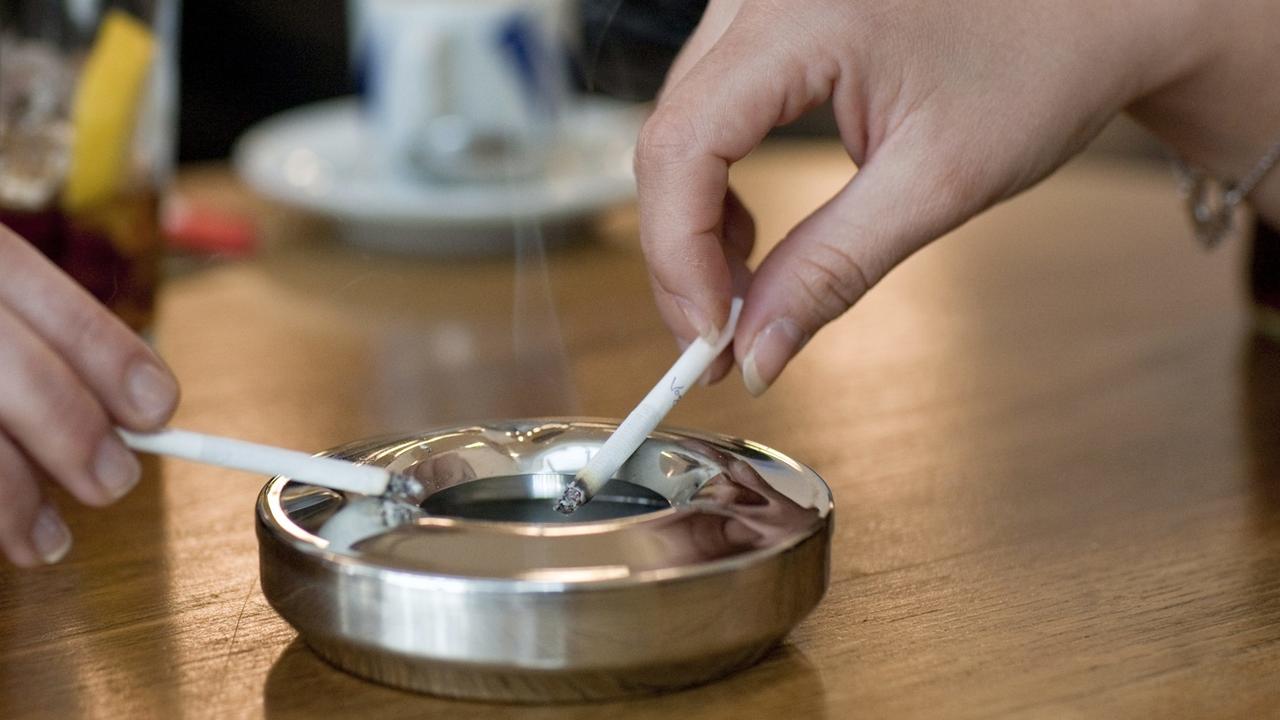 Une personne fume une cigarette dans un café. [KEYSTONE - ALESSANDRO DELLA BELLA]