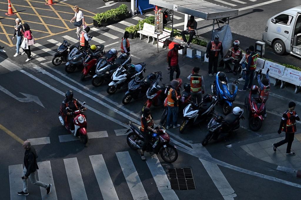 Des chauffeurs de motos-taxis de Bangkok attendent leurs clients à l'ombre. [AFP - MANAN VATSYAYANA]