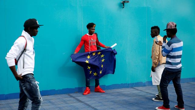 Un migrant africain tenant un drapeau de l'Union européenne à bord d'un ferry à destination d'Algésiras (en Espagne). [Reuters - Juan Medina]