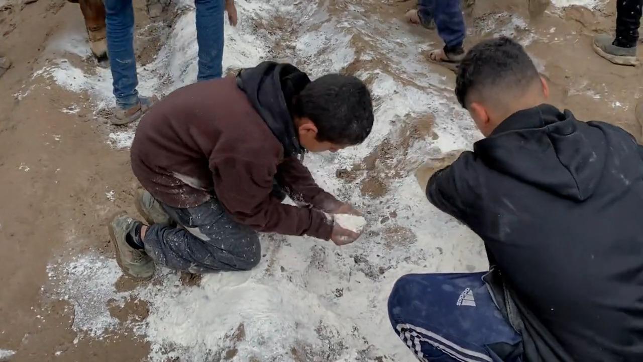 Des enfants ramassent de la farine éparpillée au sol après une livraison de nourriture. [Top Hat / ITV]