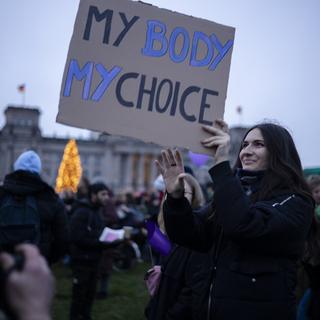 Une femme tenant une pancarte lors d'une manifestation pour le droit à l'avortement à Berlin, Allemagne. 7 décembre 2024. [AP Photo/Keystone - Markus Schreiber]