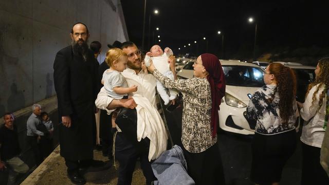 Des personnes se mettent à l'abri sur le bord de la route alors qu'une sirène retentit pour avertir de l'arrivée de roquettes sur une autoroute en direction de Jérusalem, le mardi 1er octobre 2024. [Keystone - AP Photo/Ohad Zwigenberg]