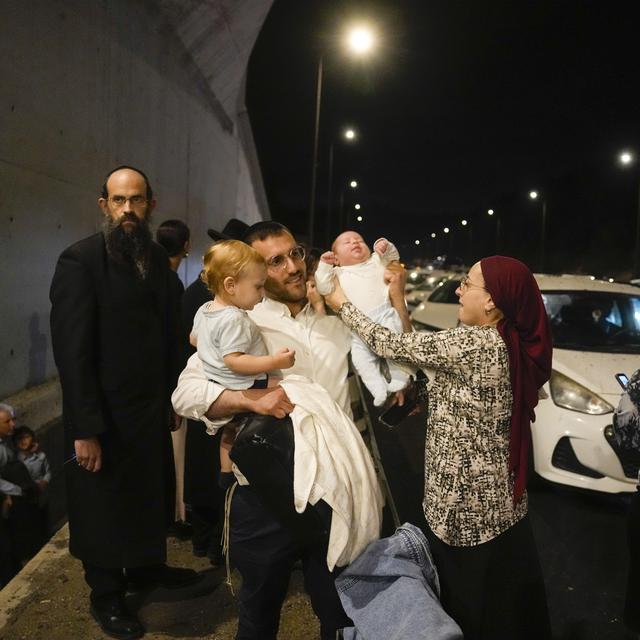 Des personnes se mettent à l'abri sur le bord de la route alors qu'une sirène retentit pour avertir de l'arrivée de roquettes sur une autoroute en direction de Jérusalem, le mardi 1er octobre 2024. [Keystone - AP Photo/Ohad Zwigenberg]