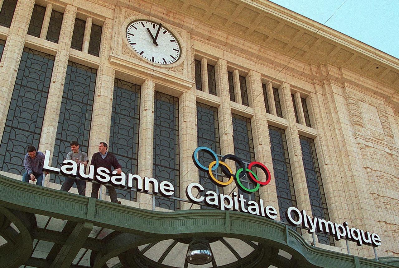 L'installation des anneaux olympiques sur la gare de Lausanne en 1997. [KEYSTONE - FABRICE COFFRINI]