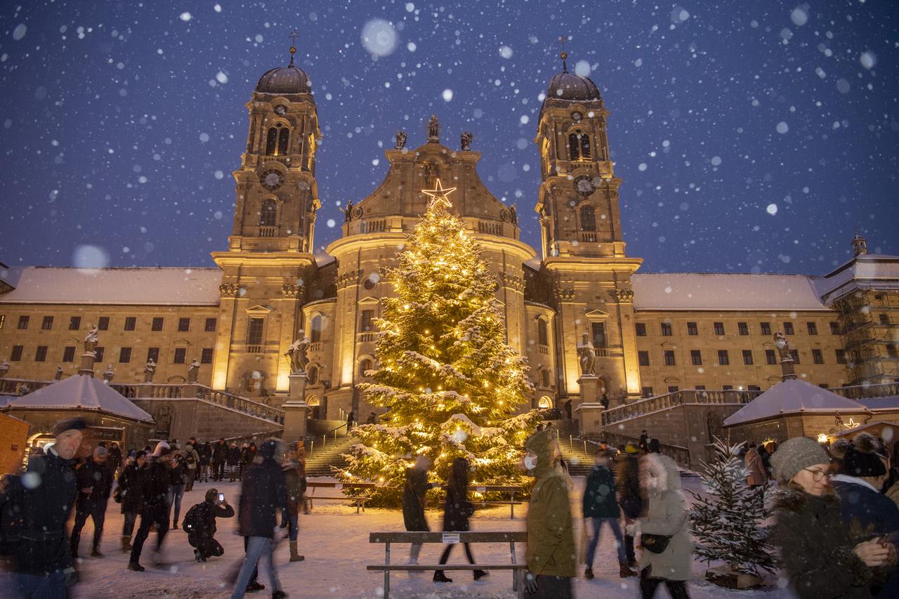 Le traditionnel marché de Noël sur la place de l'abbaye d'Einsiedeln (SZ) par temps de neige, le dimanche 28 novembre 2021. [KEYSTONE - URS FLUEELER]