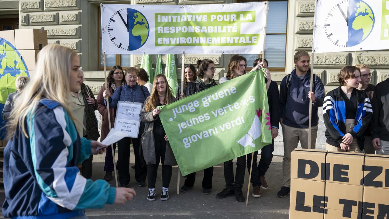 Des membres des Jeunes Verts suisses déposent l'initiative pour la responsabilité environnementale, le mardi 21 février 2023 à Berne. [Keystone - Peter Schneider]