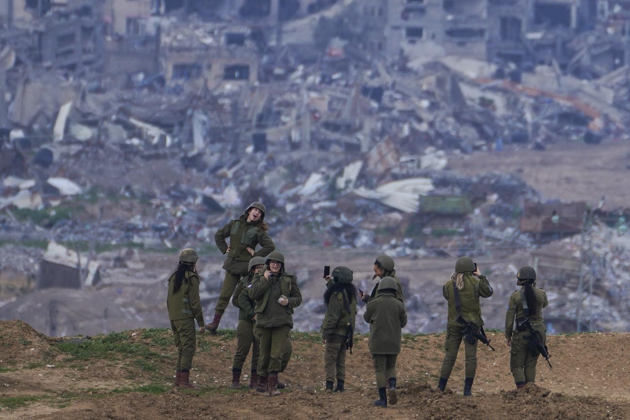 Une militaire israélienne pose pour une photo prise par une autre soldate sur une position à la frontière de la bande de Gaza, dans le sud d'Israël, lundi 19 février 2024. [KEYSTONE - TSAFRIR ABAYOV]