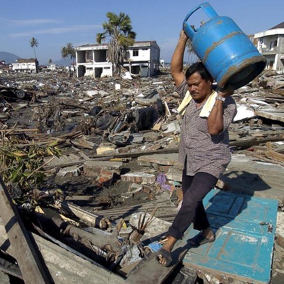 Un homme récupère un bidon dans sa maison détruite après le tremblement de terre et le tsunami qui ont frappé la province d'Aceh en Indonésie le 26 décembre 2004. [AFP - BAY ISMOYO]