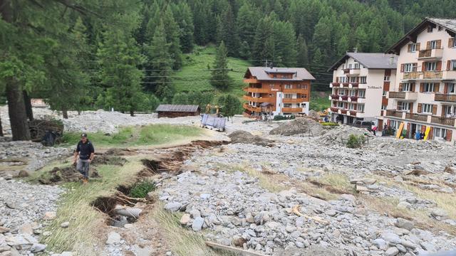 A Saas-Grund (VS), la route cantonale a été déblayée, mais des tas de matériaux mélangés à de la boue recouvrent encore les trottoirs, le 2 juillet 2024. [RTS - EMILIEN VERDON]