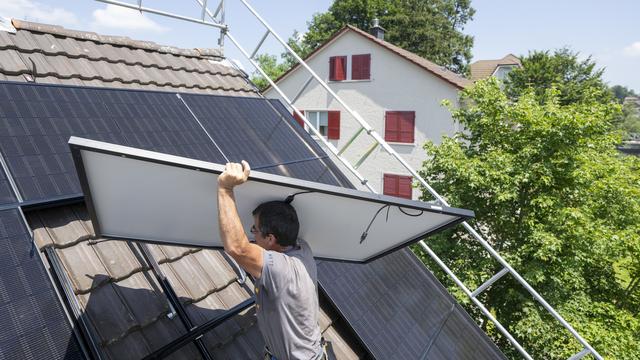 Der Installateur Beat Wolfisberg von der Firma BeNetz bei der Instalation einer Solar und Photovoltaikanlage auf dem Dach eines Einfamilienhaus an der Brambergstrasse in der Stadt Luzern am Dienstag, 25. Juni 2024.(KEYSTONE/Urs Flueeler) [Keystone - Urs Flueeler]