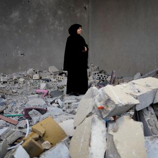 Une femme se tient sur des décombres dans la ville de Type, au Liban, le 27 novembre 2024. [Reuters - Adnan Abidi]