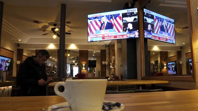 Un homme regarde son téléphone dans un café parisien. [Keystone/AP Photo - Aurelien Morissard]