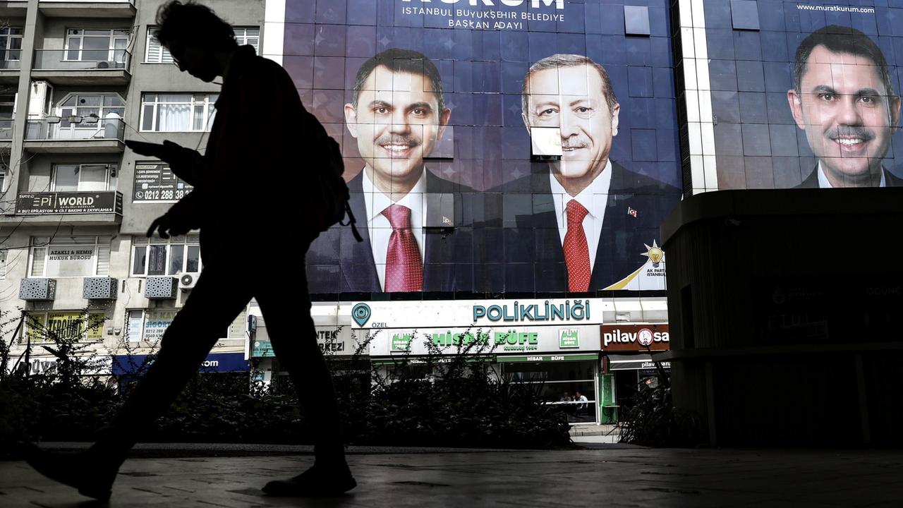 Une personne devant des affiches du parti d'Erdogan. [Keystone/EPA - Erdem Sahin]
