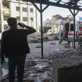 Un homme prend des photos d'une ambulance endommagée après une frappe aérienne à l'extérieur d'un complexe hospitalier à Idlib. [Ghaith Alsayed - AP Photo]