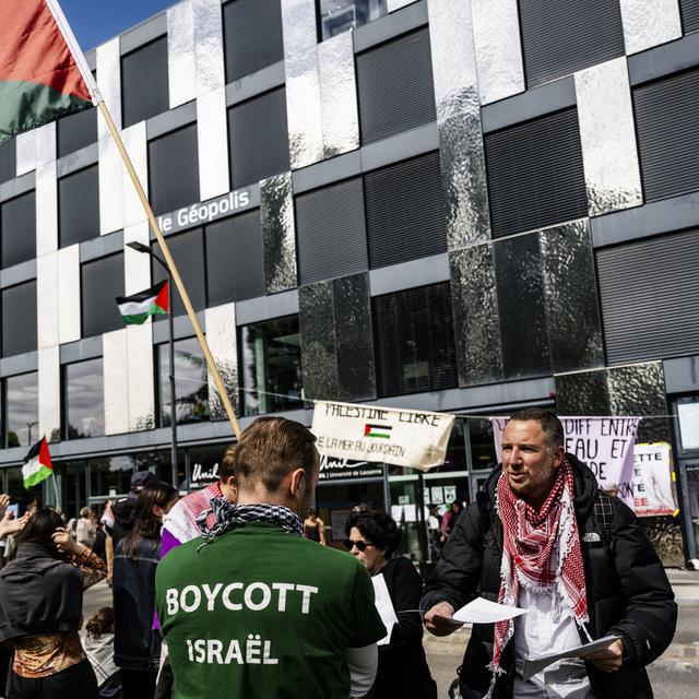 Joseph Daher, professeur invité à l'université de Lausanne, distribue des documents aux militants pro-palestiniens qui occupe un bâtiment de l'Unil. [Keystone - Jean-Christophe Bott]