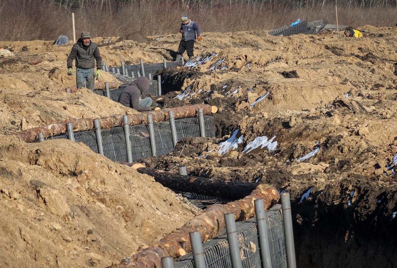 Des travailleurs renforcent avec des rondins une tranchée nouvellement construite, faite dans le cadre d'une nouvelle ligne de fortification, dans la région de Kharkiv, le 12 mars 2024. [REUTERS - Vyacheslav Madiyevskyy]