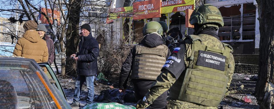 Un agent du Comité d'enquête russe examine les corps des victimes du bombardement du marché alimentaire à Donetsk, dans la région de Donetsk, dans l'est de l'Ukraine, le 21 janvier 2024. [Keystone - EPA/ALESSANDRO GUERRA]