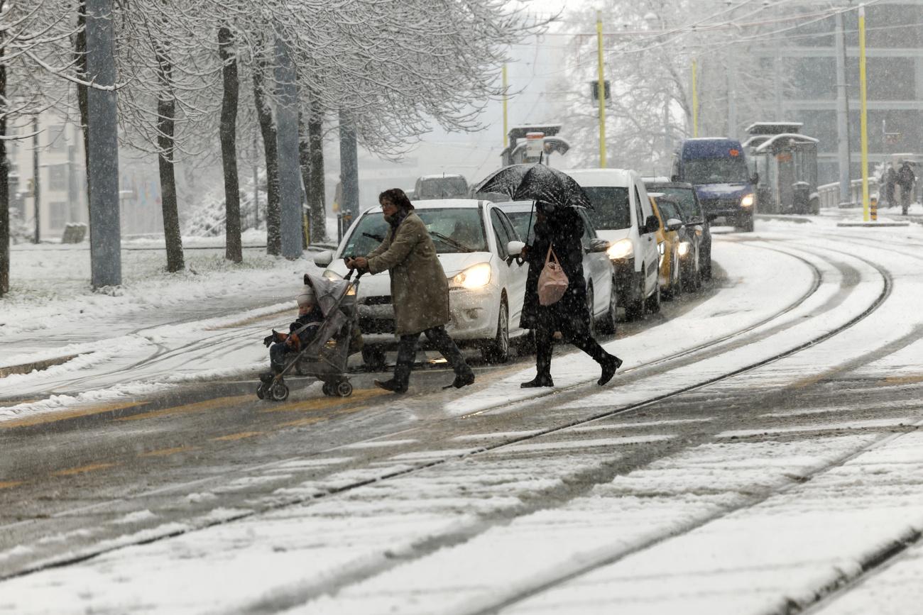 Des personnes traversent une route enneigée à Genève. [Keystone - Salvatore Di Nolfi]