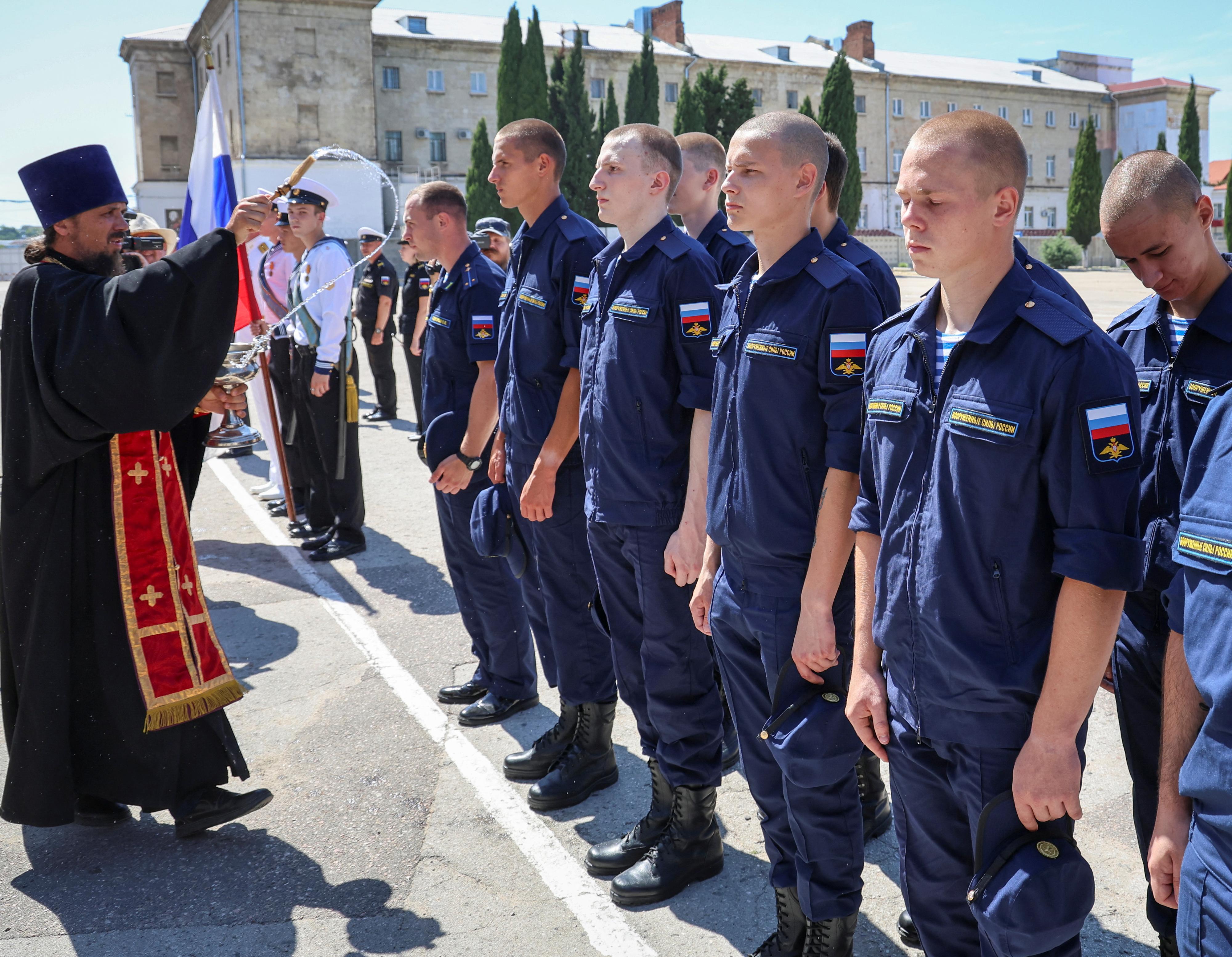 Un prêtre orthodoxe bénit des conscrits russes appelés au service militaire avant leur départ pour les garnisons d'un centre de recrutement à Sébastopol, en Crimée, le 6 juillet 2023 (image d'illustration). [REUTERS - ALEXEY PAVLISHAK]