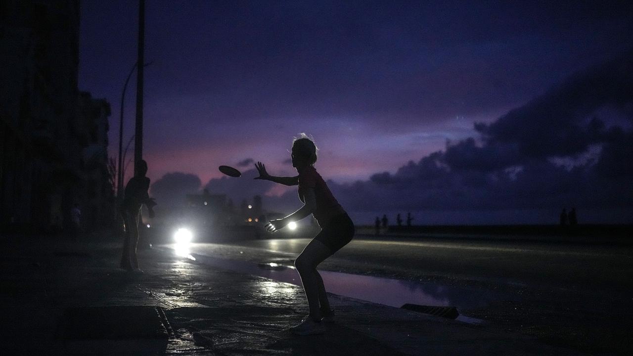 A woman prepares to catch a tossed frisbee during a massive blackout after a major power plant failed in Havana, Cuba, Friday, Oct. 18, 2024. [AP Photo/Keystone - Ramon Espinosa]