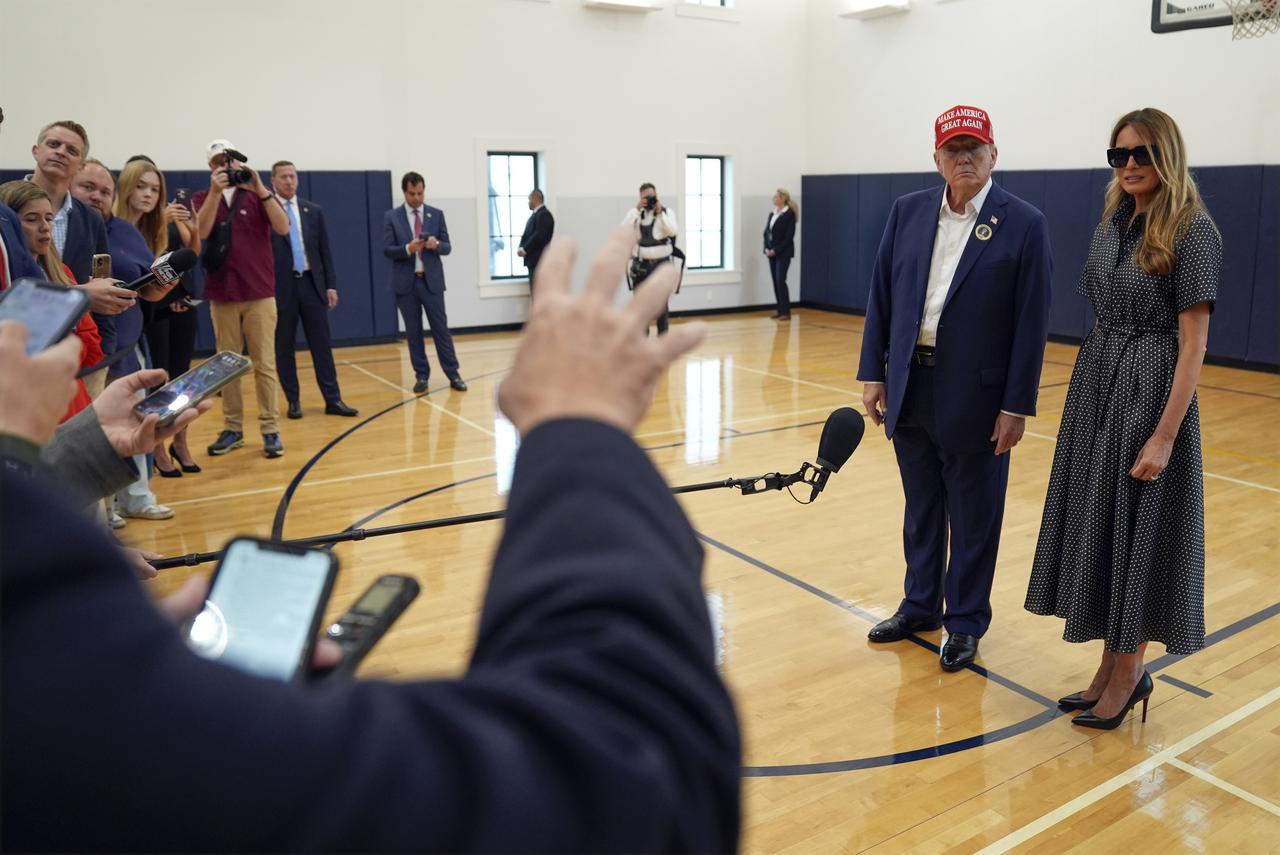 Donald Trump, accompagné de son épouse Melania Trump, répond à des question au bureau électoral de Palm Beach où il a voté. [KEYSTONE - EVAN VUCCI]